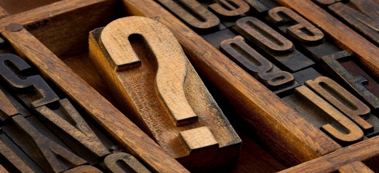 question mark - vintage wooden letterpress type block in old typesetter drawer among other letters stained by ink